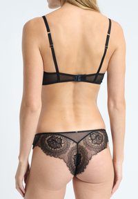 Black lace lingerie set featuring a sheer back, floral patterns, and adjustable straps with a hook closure on the bra.