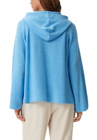 Hellblauer Kapuzenpullover mit gerippter Textur, lockerer Passform und langen Ärmeln. Hat einen Saum, der auf der Taille endet.