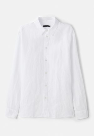 Camicia bianca a maniche lunghe con bottoni, realizzata in tessuto testurizzato. Presenta un colletto classico e una chiusura frontale con bottoni piccoli e rotondi.
