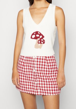 Top de punto blanco sin mangas con diseño de setas en rojo y beige, combinado con una falda a cuadros rojos y blancos con botones en la parte delantera.