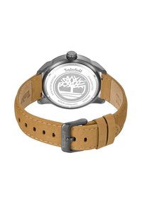 Reloj Timberland con correa de piel beige, acabado texturizado, caja de acero inoxidable negro, logo grabado en la parte posterior, diseño de esfera de color plateado.