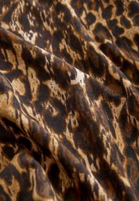 Leopardenmusterstoff mit einer Mischung aus braunen, schwarzen und beigen Tönen. Glatte Textur mit unregelmäßigem Muster und sanftem Fall.