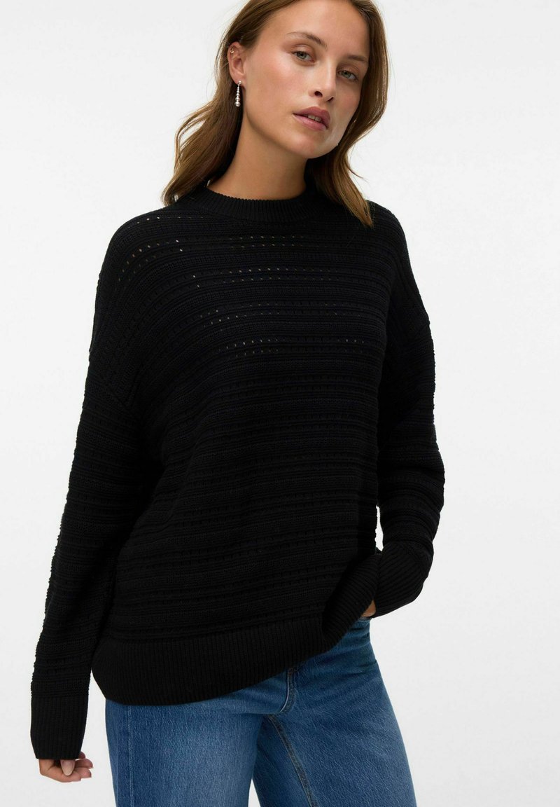 Maglione nero lavorato a maglia con righe orizzontali, scollo rotondo e polsini a coste. Il tessuto presenta una finitura testurizzata con piccoli fori.