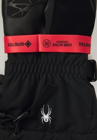 Guante aislante negro con palma de cuero suave, correa de muñeca ajustable roja con etiqueta "GORE-TEX" y detalle de logo de araña blanca.