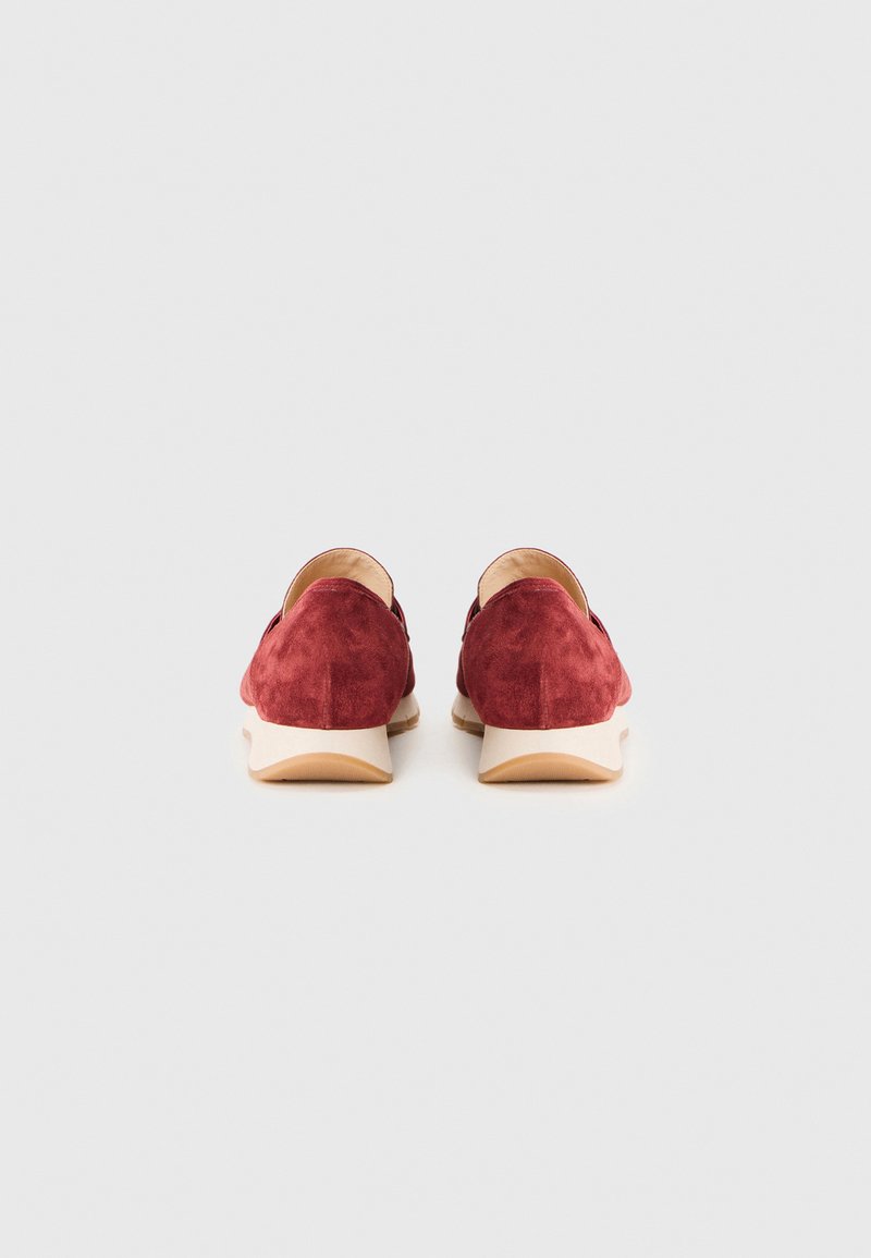 Rode suède instappers met een gestructureerde afwerking en een beige rubberen zool, voorzien van een amandelvormige neus en minimale details.