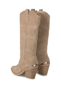 Botas de vaquero de ante beige con costuras decorativas, punteras puntiagudas y tacones apilados gruesos con acentos metálicos.