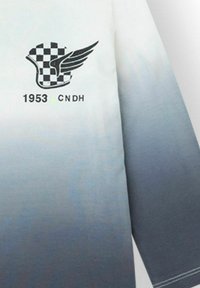 Camisa de manga larga con un degradado de blanco a gris oscuro. Presenta un logo de ala a cuadros en negro y el texto "1953 CNDH". Textura suave.