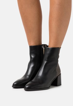 Schwarze Leder-Stiefeletten mit Blockabsatz und seitlichem Reißverschluss, mit einem gemusterten Stoffakzent in Braun auf der Rückseite.