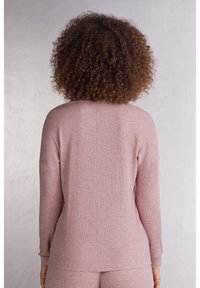 Ljusrosa ribbad långärmad topp med en avslappnad passform. Har bred halsringning, sänkta axlar och textilerad tyg.