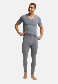 Camiseta deportiva gris con cuello en V y mangas cortas, combinada con leggings grises. El material es suave y ajustado, enfatizando un aspecto aerodinámico.