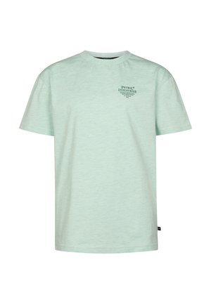 Blond jongetje staat, draagt een lichtgroen T-shirt met korte mouwen, blauwe jeans en witte sneakers tegen een effen witte achtergrond.