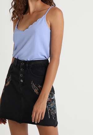 Lichtblauw, gegolfd tanktop gecombineerd met een zwarte denimrok met kleurrijke bloemenborduursels en een sluiting met vijf knopen aan de voorkant.