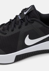Černá sportovní bota s síťovaným svrškem, zesílenými prvky a bílým logem swoosh. Má texturovanou podrážku a ploché tkaničky.