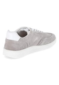 Sneaker in suede grigio chiaro con linguetta sul tallone bianca, lacci bianchi e suola in gomma bianca strutturata, vista da un angolo posteriore laterale.