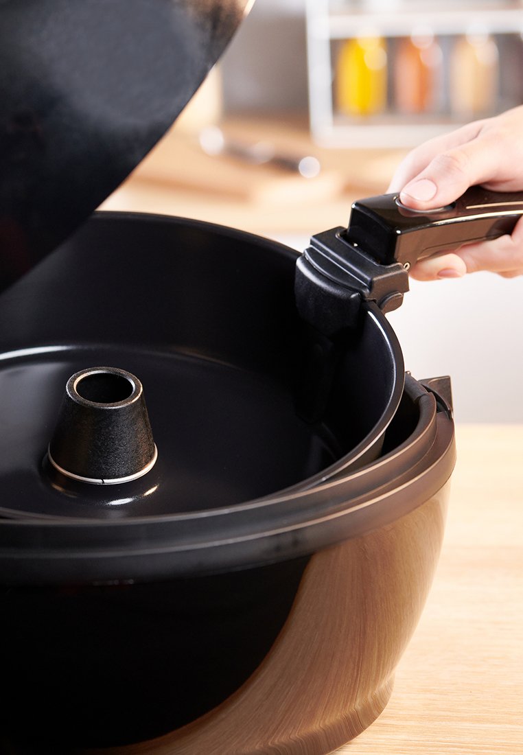 Schwarzer zylindrischer Kochtopf mit abnehmbarem Deckel und einem zentralen Kegel zum Dampfen. Glatte Innenfläche und stabiler schwarzer Griff.