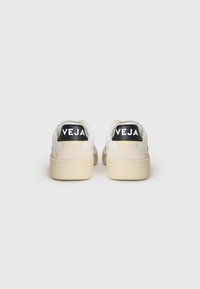 Sneakers bianchi con tomaia in pelle liscia, suola beige, linguetta sul tallone nera con la scritta "VEJA" e design minimalista.