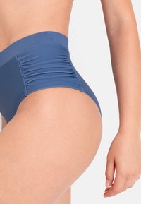 Visokotakšne kopalne hlačke temno modre barve z detajli ob straneh. Gladek, elastičen material, zasnovan za udobje in prileganje.