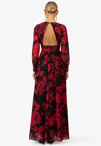 Abito maxi nero con motivo floreale rosso, maniche lunghe, schiena scoperta, vita svasata e gonna fluida. Tessuto leggero con lucentezza.