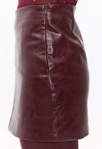 Bordeaux lederen minirok met een glanzende afwerking, voorzien van een zijrits en een zachte textuur, speciaal ontworpen voor een getailleerde pasvorm.