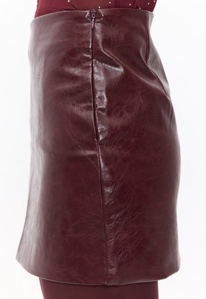 Mini-jupe en cuir bordeaux avec une finition brillante, dotée d'une fermeture éclair sur le côté et d'une texture lisse, conçue pour une silhouette ajustée.