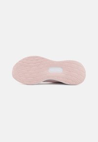 Roze rubberen zool van een sneaker met textuur en een cirkelpatroon. Bevat een witte tussenzool en een glad, rond uiteinde.