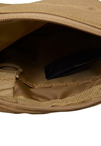 Tan fabric pouch with a zipper closure. Interior shows a smooth texture, a small loop, and a black label on the side.