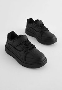 Baskets noires avec une finition en cuir lisse, dotées de doubles sangles, de lacets et d'un design de bout perforé. Semelle en caoutchouc épaisse pour une durabilité accrue.