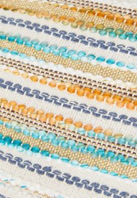 Tekstil med horisontale striper i beige, blå, grønn, oransje og gull, med varierende teksturer inkludert pom-poms og metalltråd accenter.