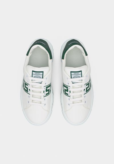 Baskets en cuir blanc avec bandes logo Versace vertes et languettes vertes au talon, modèle à lacets, vues de dessus sur un fond blanc.