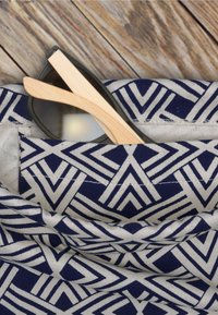 Blå och vit mönstrad tygväska med geometrisk design; bambusolglasögon delvis synliga i fickan. Slät textur och modern form.