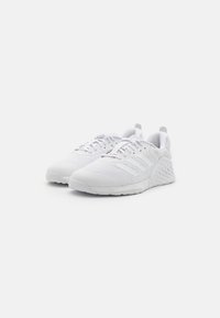 Chaussures de sport blanches avec une tige en mesh, des superpositions texturées, un laçage traditionnel et une semelle à motif pour l'adhérence et le soutien.