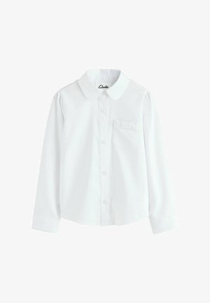 Fehér, hosszú ujjú gombos ing, galléros nyakkal, egy kis mellzsebbel és puffos vállakkal. Az anyag simának és könnyűnek tűnik.