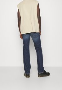 Top senza maniche beige, jeans blu scuro con leggera scoloritura e scarpe in pelle nere. Tessuto morbido e design a vestibilità regolare.
