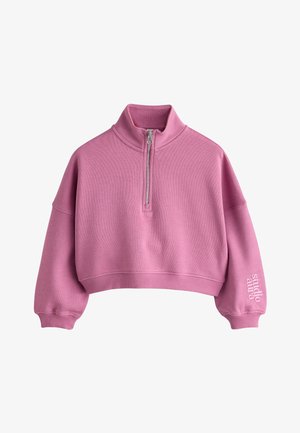 Lyserød cropped sweatshirt med kvart lynlås, høj krave, ribstrikkede manchetter og kant samt teksten "studio aura" på venstre ærme.