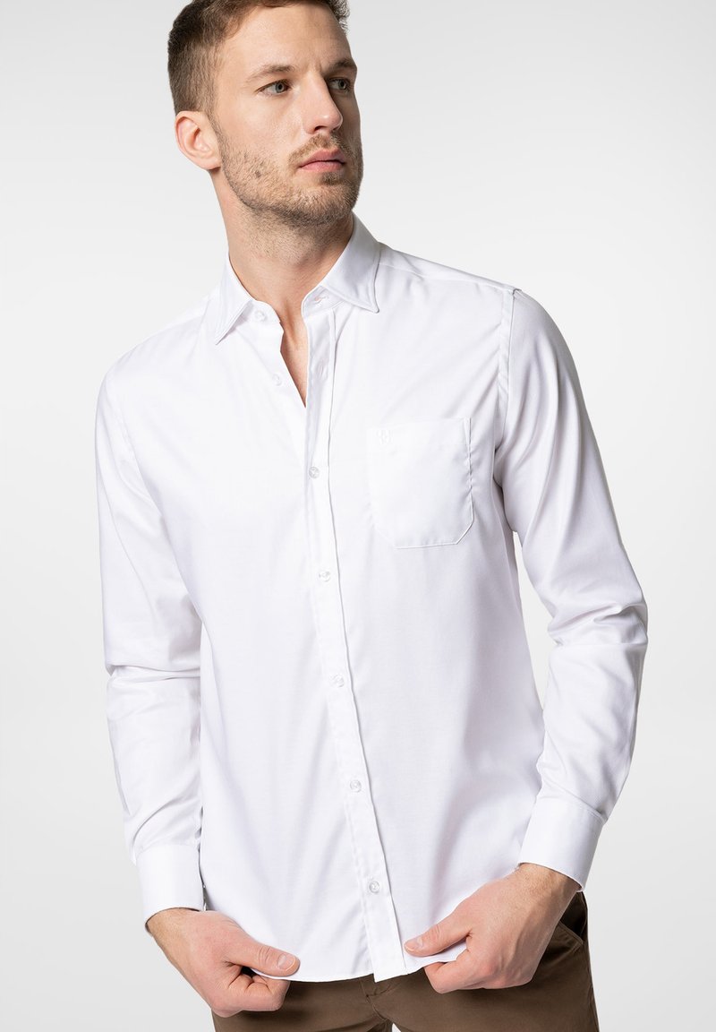 Biała koszula zapinana na guziki z mieszanki bawełny, z kieszonką na piersi, długimi rękawami i klasycznym kołnierzykiem, prezentowana na męskim modelu.
