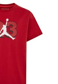 Maglietta in cotone rossa con silhouette in bianco e nero di un giocatore di basket e il numero "23" in rosso bold, maniche corte, colletto rotondo.