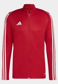 Rote Sportjacke mit weißen Streifen an den Ärmeln. Verfügt über einen durchgängigen Reißverschluss, einen hohen Kragen, eine glatte Textur und ein gesticktes Logo auf der Brust.