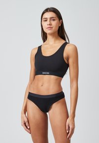 Zwarte katoenen sportbeha en bijpassende bikini slip met een zachte elastische band met de merknaam "SNOCKS." Glad textuur met minimale details.