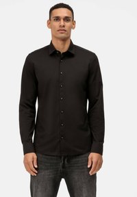 Schwarzes, langärmliges Hemd mit Knopfleiste und Kragen, schlichtes Design und schwarzen Knöpfen, kombiniert mit dunklen Jeans. Glatte Stoffstruktur.
