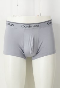 Graue Baumwoll-Boxershorts mit enganliegendem Schnitt, ausgestattet mit einem schwarzen Calvin Klein-Logo am Bund und einer glatten, dehnbaren Textur.