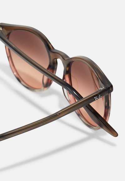 Lunettes de soleil écaille de tortue avec des verres bruns dégradés, forme classique en œil de chat, branches fines et logo Ray-Ban sur une branche.