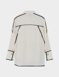 Μπλούζα μακρυμάνικη κρεμ με μαύρες λεπτομέρειες και μανσέτα με κουμπιά. Διαθέτει γιακά και χαλαρή εφαρμογή με διακριτικές πιέτες στο πίσω μέρος.