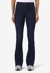 Mørkeblå denim vide bukser med høy midje, som har lommer foran og bak, samt en glatt tekstur. Stylet med en tettsittende hvit topp.