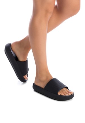 Chanclas negras con un upper texturizado, punta abierta y suela gruesa. Diseñadas para una fácil colocación, son adecuadas para su uso en interiores o exteriores.