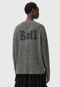 Harmaa neulottu villapaita, jossa on teksturoitu pinta ja mustalla selässä sana "Roll". Pitkät hihat ja rento istuvuus.