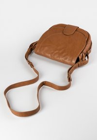 Brun læder crossbody taske med kurvet form og klaplukning, justerbar rem og glat tekstur. Har et minimalistisk design.