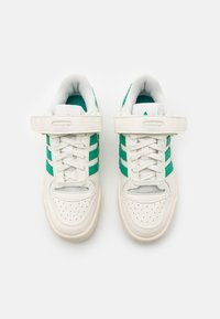 Vita sneakers med gröna ränder, syntetiskt läder, perforerad tå, vadderad krage, kardborreband och snörning för säker passform.