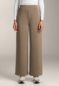 Široké nohavice z ribovaného taupe materiálu s hladkým povrchom. Majú elastický pás a siahajú po členky. V kombinácii s teniskami.