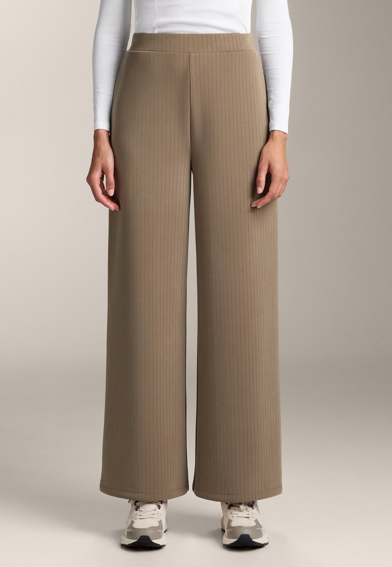 Široké nohavice z ribovaného taupe materiálu s hladkým povrchom. Majú elastický pás a siahajú po členky. V kombinácii s teniskami.