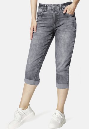 Graue Denim-Caprihosen mit umgeschlagenen Säumen, ausgestattet mit Fronttaschen und einer eleganten, glatten Textur. Kombiniert mit weißen Sneakers.